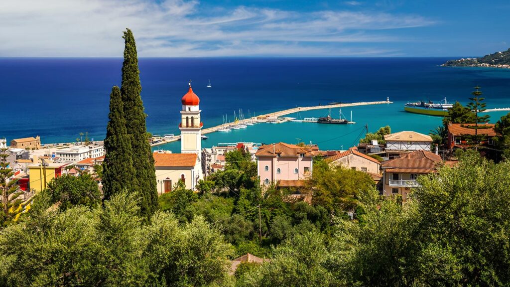 Vy över hamnen på Zakynthos med blått hav och vitkalkade hus.