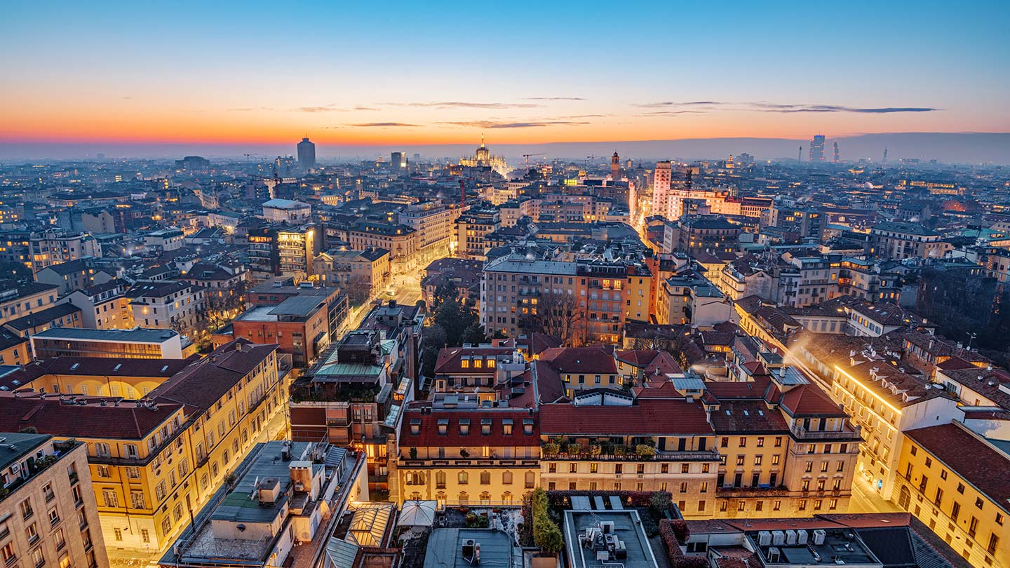 Utsikt över Milano vid skymning, med färgglada himmel och upplysta byggnader.