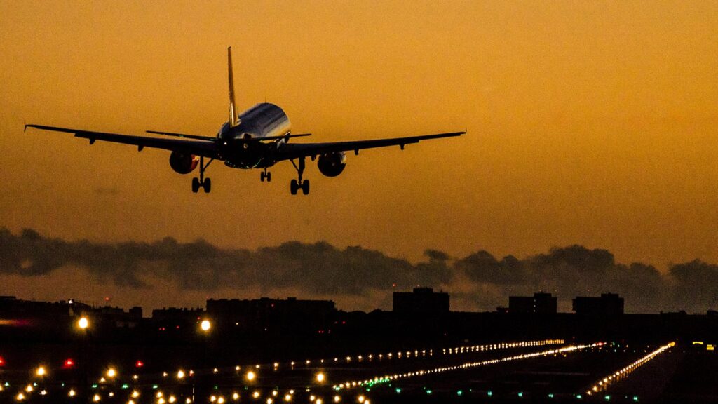 Ett flygplan landar på Palma flygplats vid solnedgång. Många ljus syns på banan.