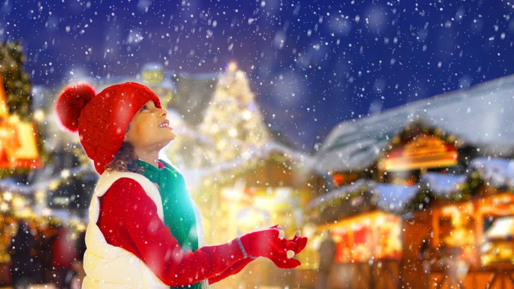 En glad person står i snön på julmarknad i Strasbourg, Frankrike.