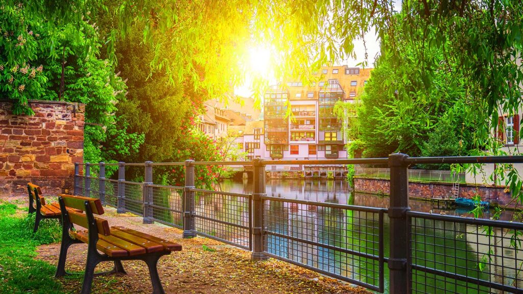 Färgglada hus i La Petite France, Strasbourg, omgivna av grönska och vatten.