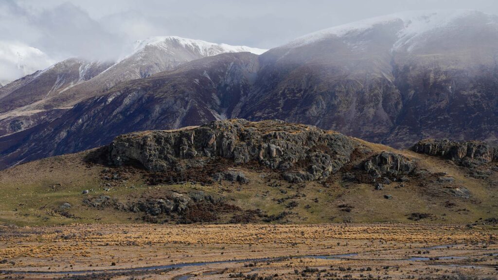 Bilden visar Edoras med stora berg och grönskande landskap i bakgrunden.