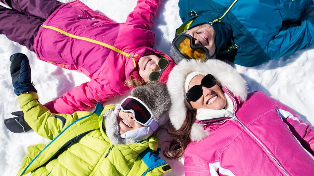 Familj leker i snön i La Plagne, Frankrike, med färgglada vinteråkläder.