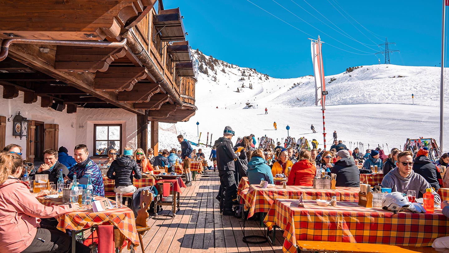 Uteservering på ett bergscafé i St. Anton am Arlberg, med snö och glada gäster.