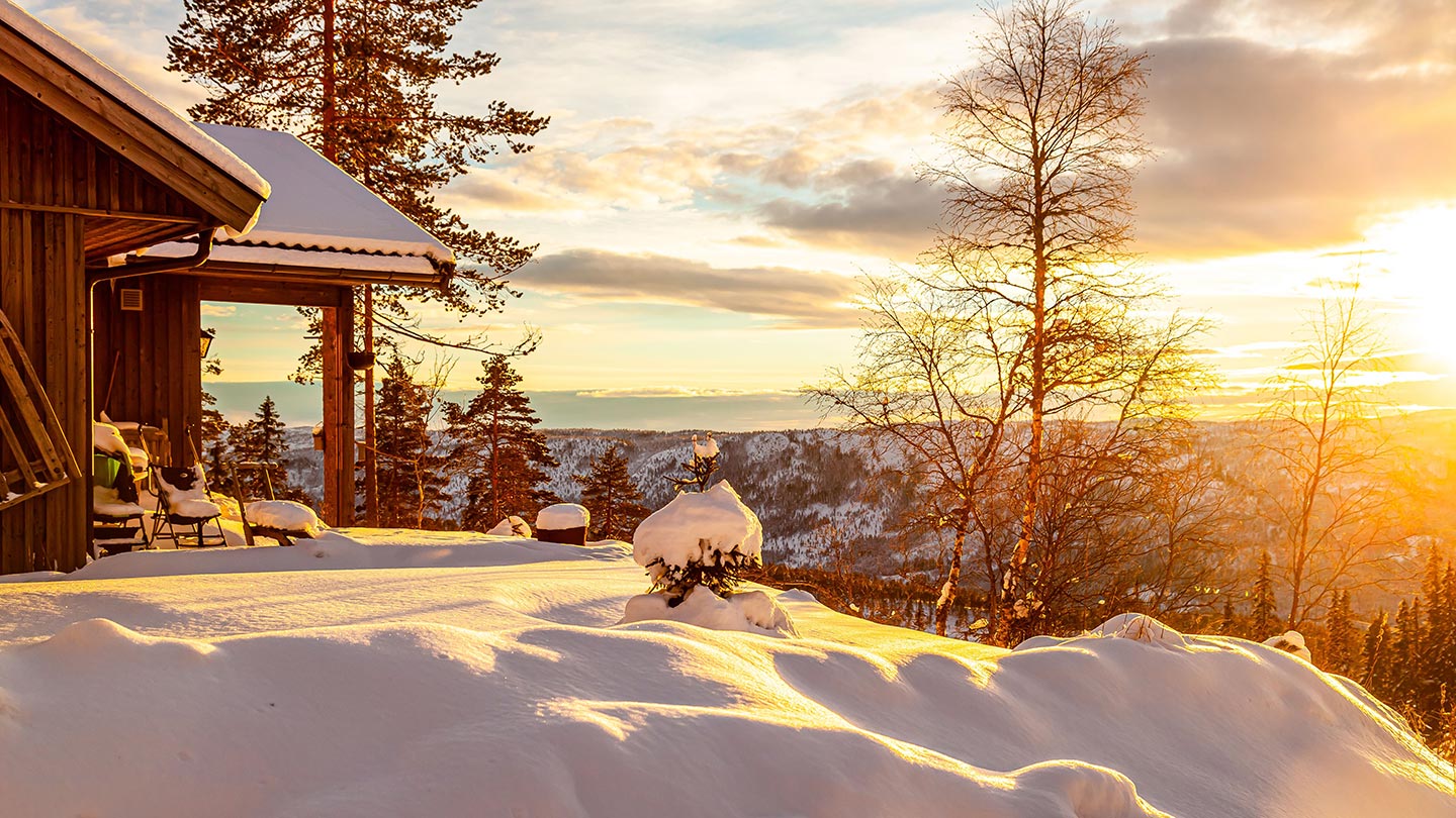 En stuga i Härjedalen, Sverige, omgiven av snö och vacker solnedgång.